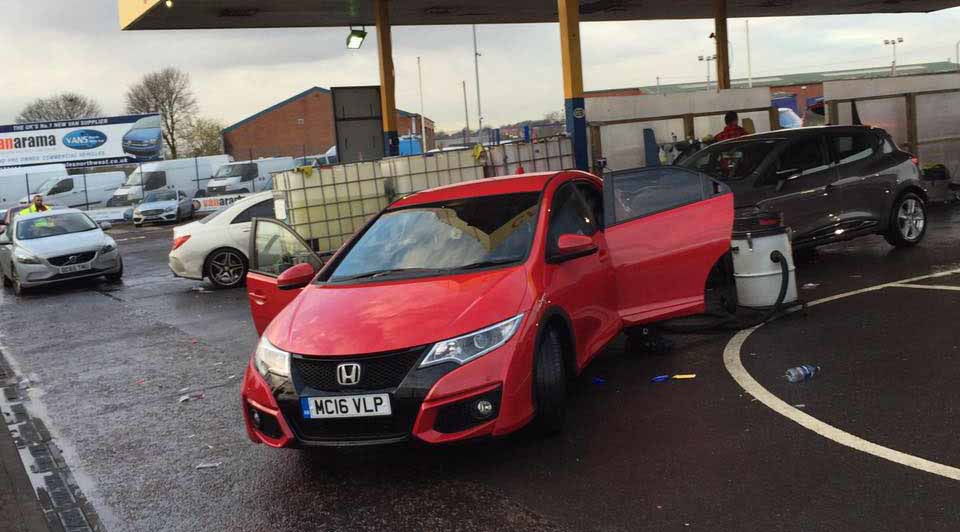 A red Honda Civic with its doors open for an interior clean in the wash bay