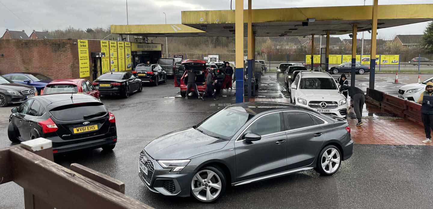 A busy forecourt at George's Car Wash with an Audi saloon and other cars queued for a hand wash